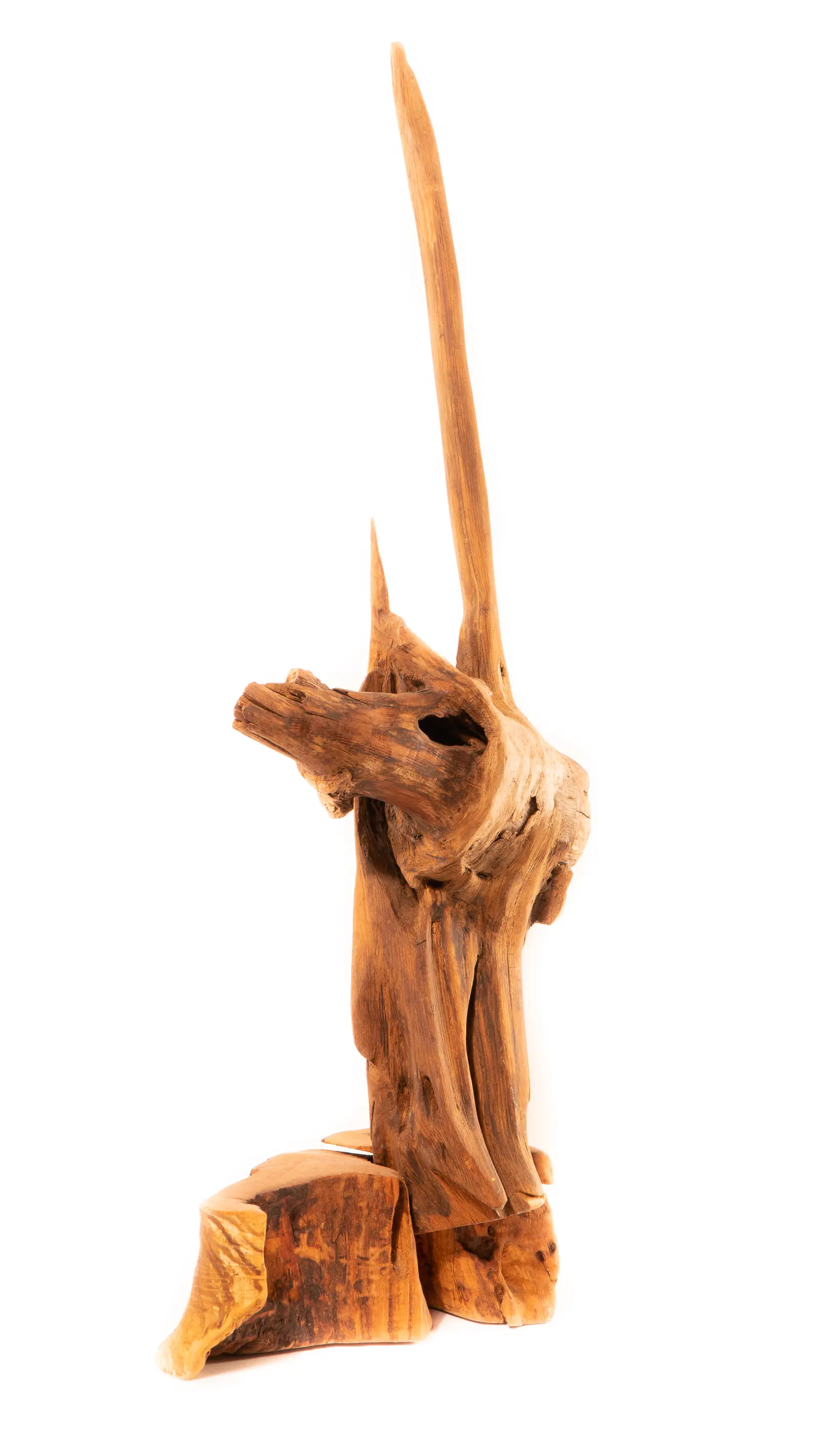 Sculpture verticale en bois : une longue pointe effilée s'élève d'une masse au visage émergent, sur une base de rondin, œuvre de Robert Bibeau