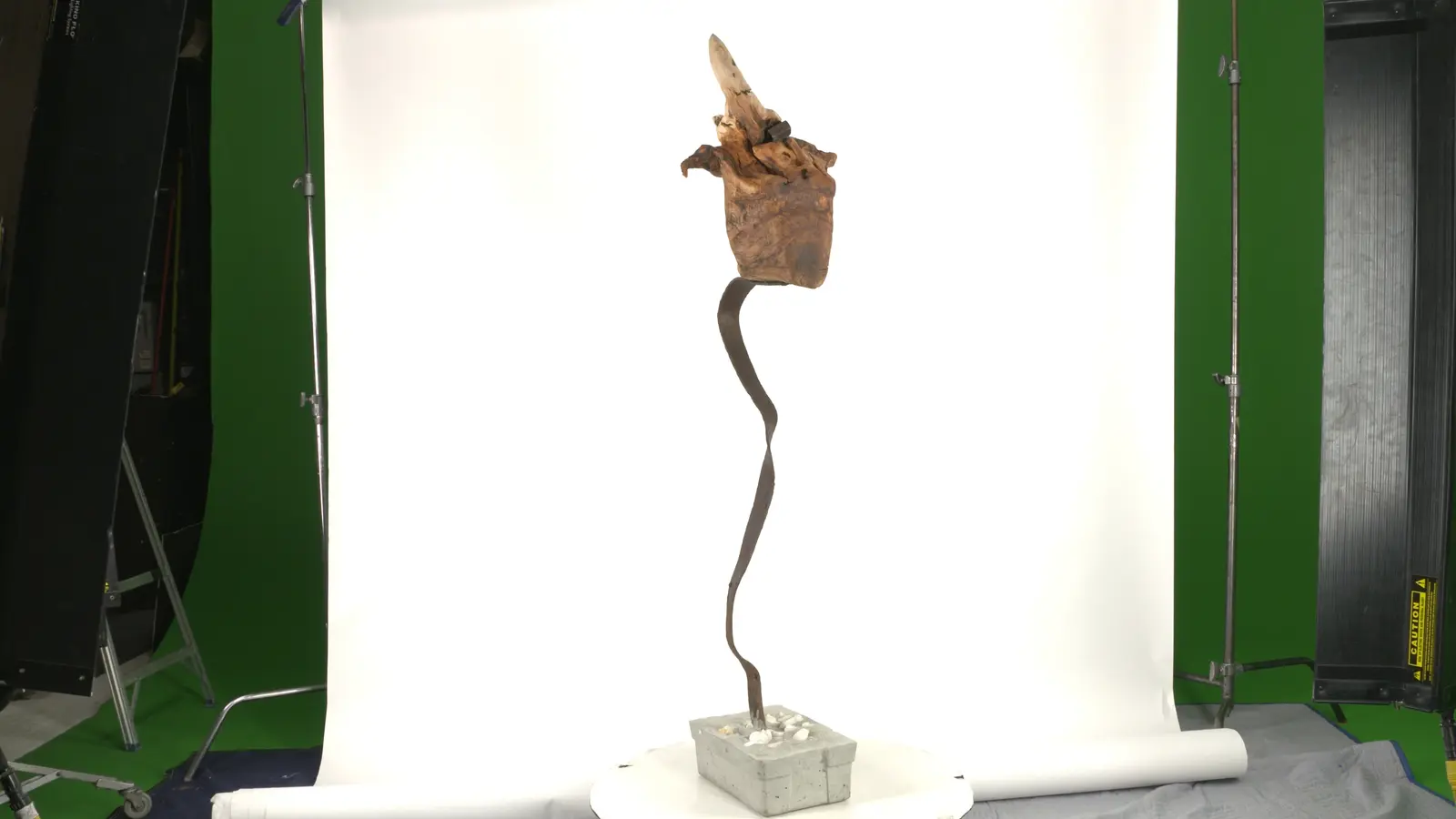 Verticale épurée — base béton avec cailloux blancs, tige métallique forgée serpentine, bloc de bois travaillé en sommet. — vue 1