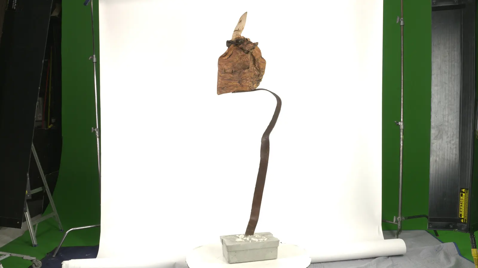 Verticale épurée — base béton avec cailloux blancs, tige métallique forgée serpentine, bloc de bois travaillé en sommet. — vue 4