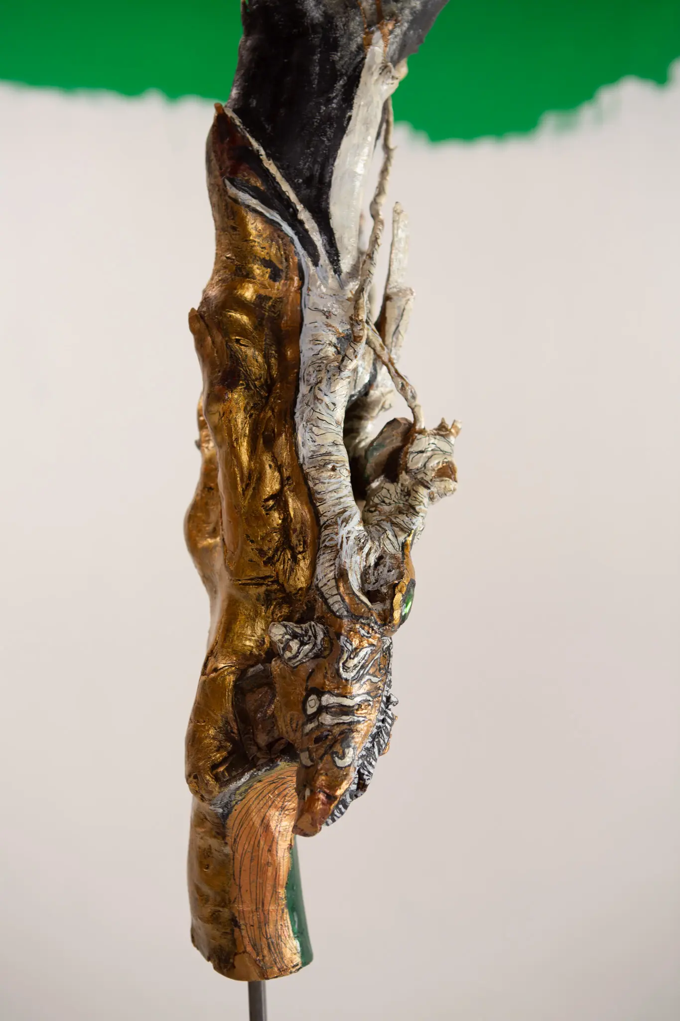Profil de la figure dressee, museau sculpte vers le bas, dorure, peinture blanche et trace de pigment vert au pied.