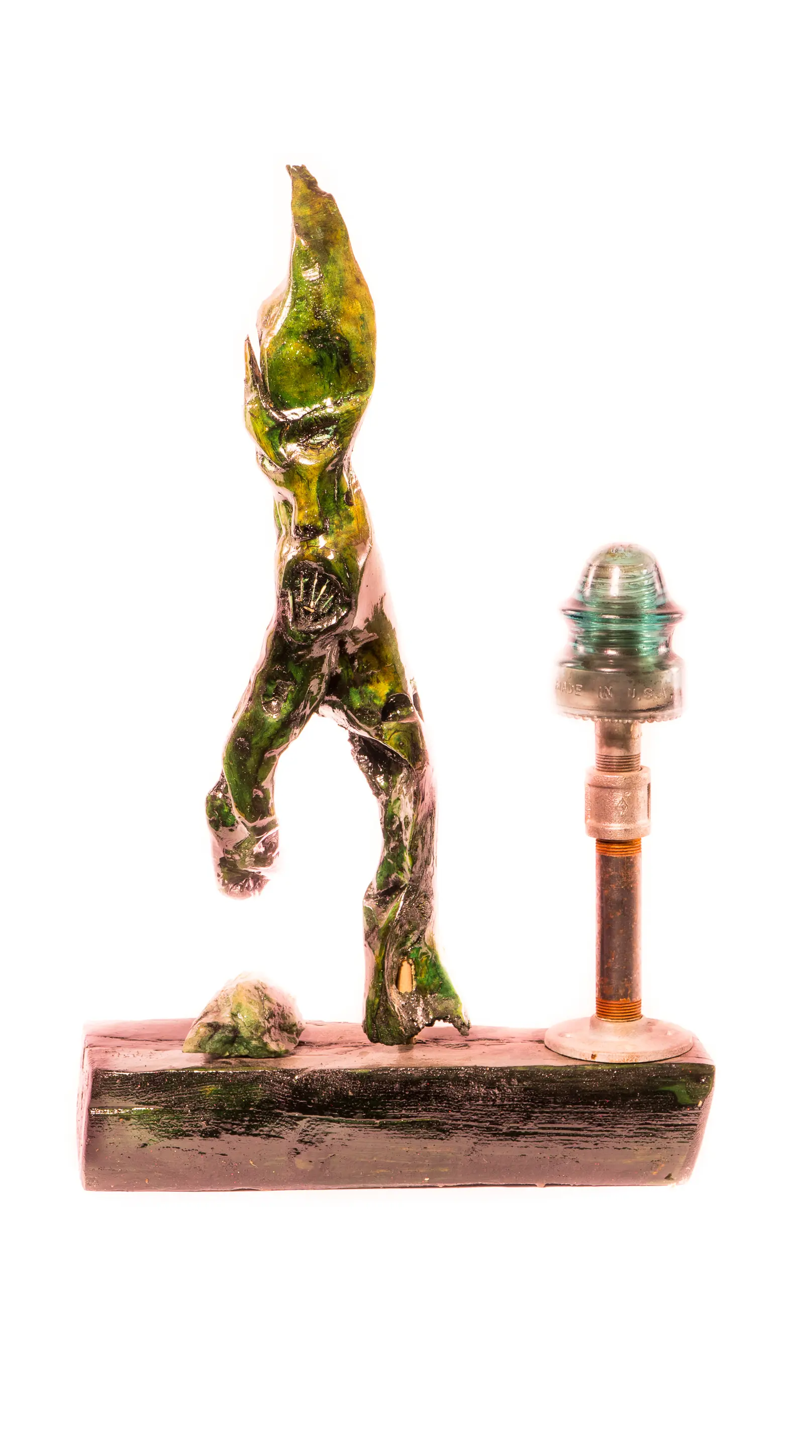 Figure verte en marche à tête de flamme, montée sur un socle noir avec un lampadaire coiffé d'un isolateur de verre, œuvre de Robert Bibeau