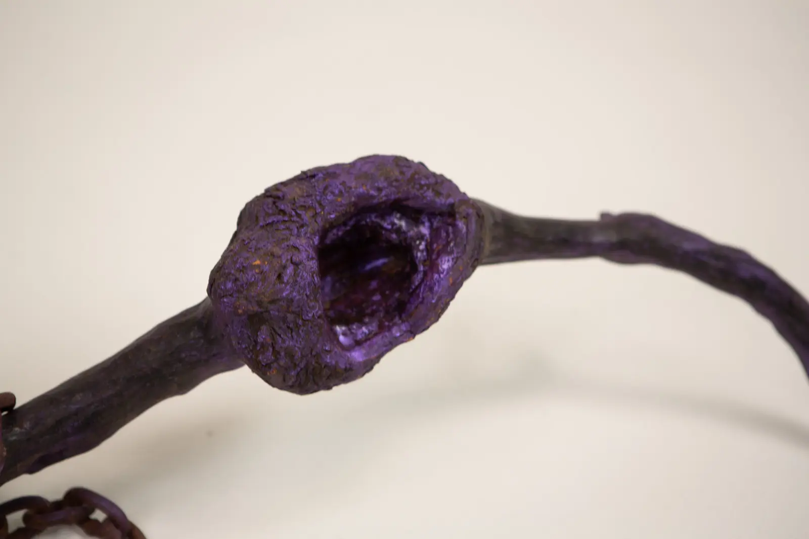 Sculpture vue de dessus en plongée, deux cavités creusées le long de la branche violette, chaîne rouillée vers l'avant.
