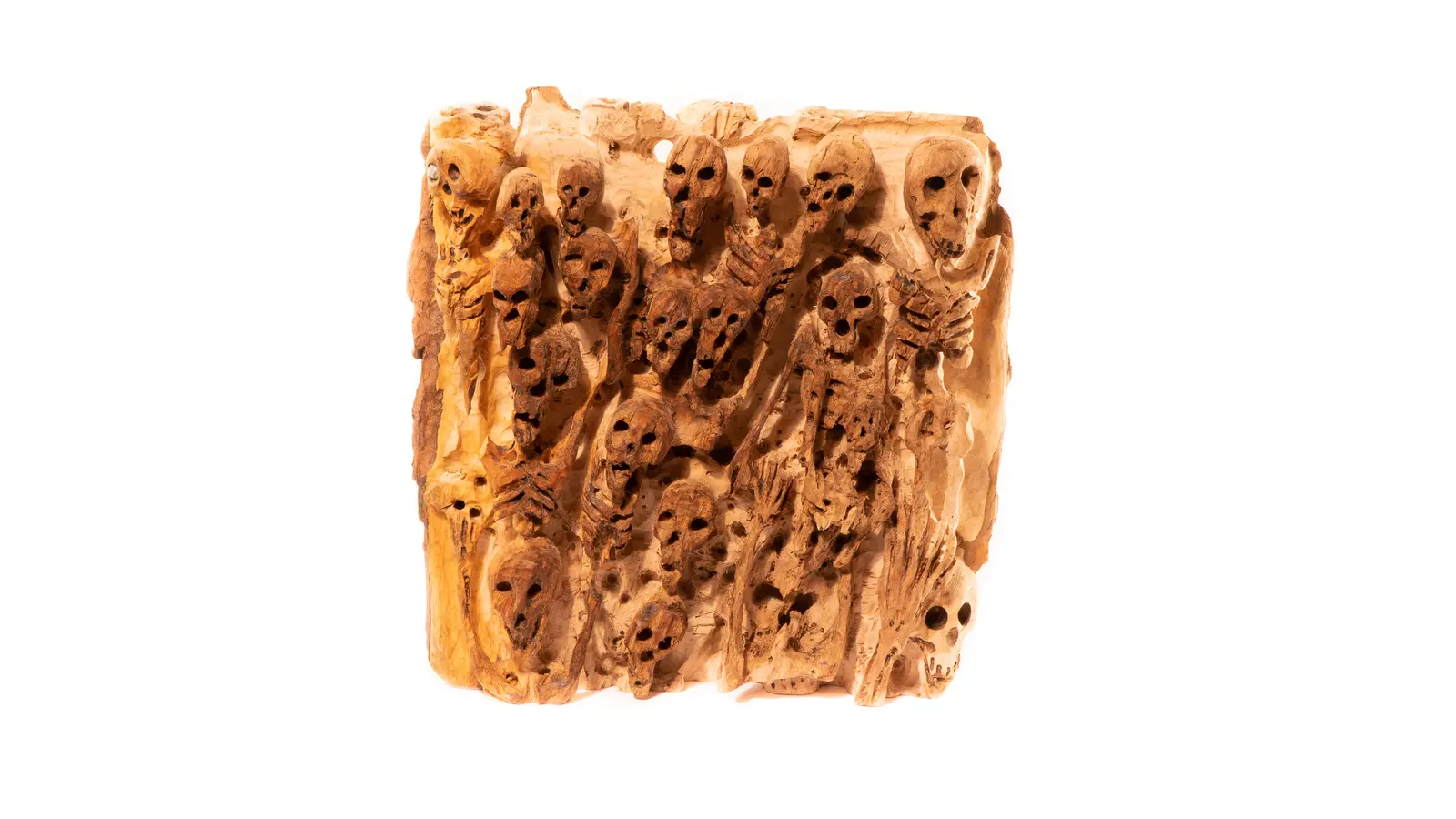Bas-relief en bois : foule serrée de crânes et de squelettes émergeant d'une dalle, vue frontale, œuvre de Robert Bibeau