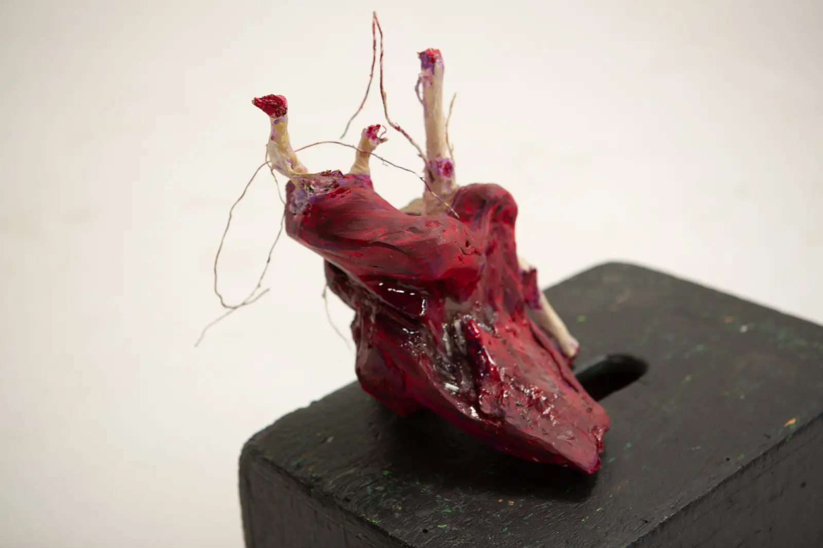 Vue rapprochée du cœur sculpté rouge montrant les éclats de miroir incrustés dans la résine et les vaisseaux ouverts.